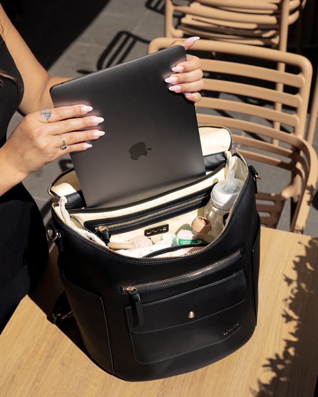 Sac à langer de luxe noir LOU·VE en cuir vegan, ouvert avec compartiment pour ordinateur, utilisé comme sac à dos et sac de bureau.