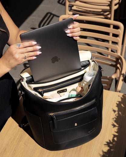 Sac à langer de luxe noir LOU·VE en cuir vegan, ouvert avec compartiment pour ordinateur, utilisé comme sac à dos et sac de bureau.